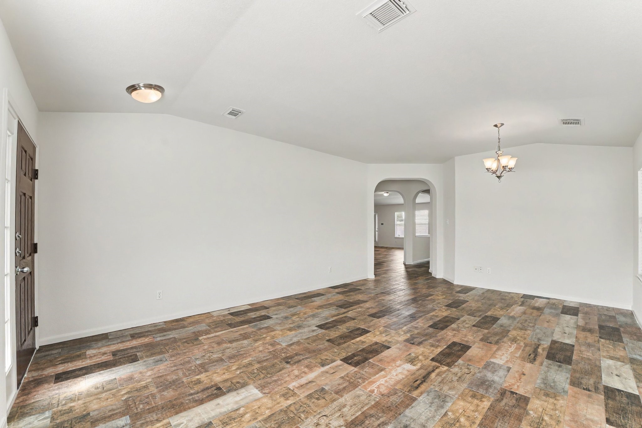 21427 Blooming Rock Lane Spring, TX 77379 - Photo 4 of 32 This spacious living area features rustic wood-look flooring, neutral walls, and a central light fixture. The open layout offers an arched entryway leading to additional rooms, enhancing flow and connectivity.