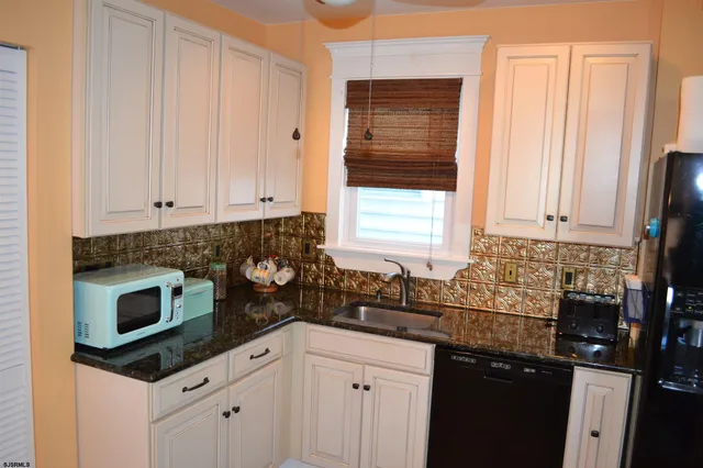 a kitchen with granite countertop white cabinets and black appliances