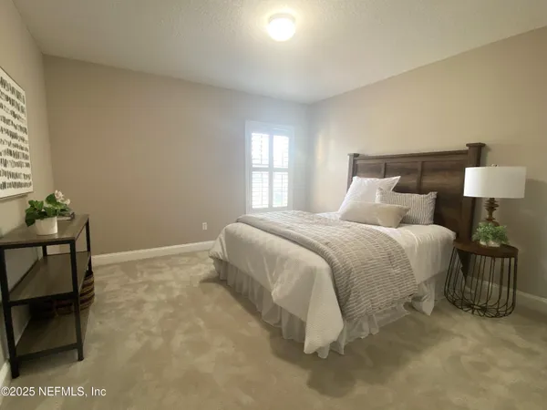 a spacious bedroom with a bed and a lamp on table