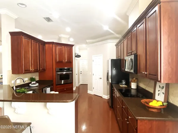 a kitchen with stainless steel appliances granite countertop a refrigerator a stove and a sink with wooden floor