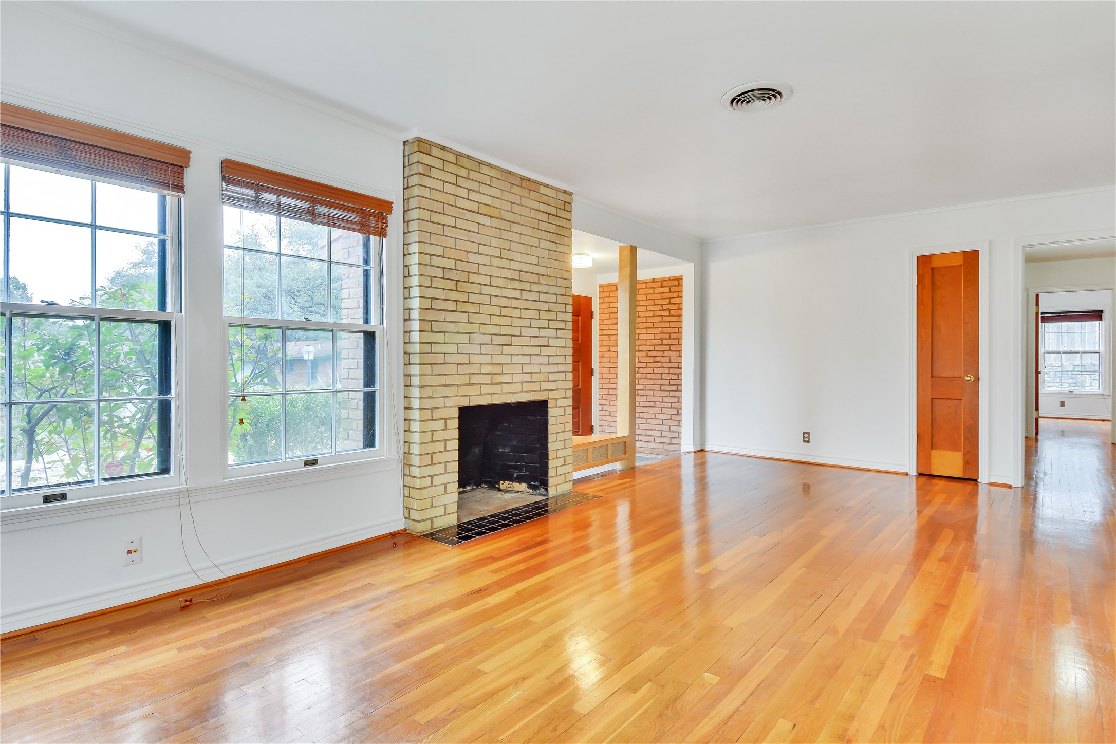 2300 Rebel Road Austin, TX 78704 - Photo 2 of 26 Golden hardwood floors extend across this living area with a prominent brick fireplace.