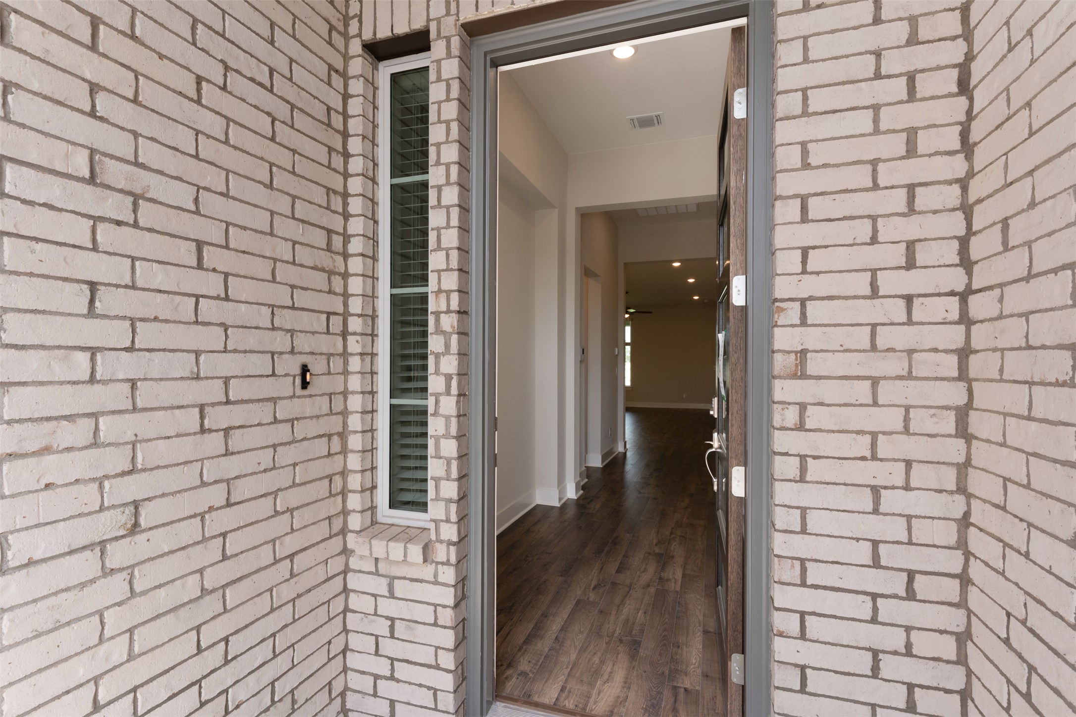 1129 Pansy Trail Georgetown, TX 78628 - Photo 3 of 29 Entryway featuring a white brick facade, wood-finish flooring, recessed lighting, and a sidelight window with blinds