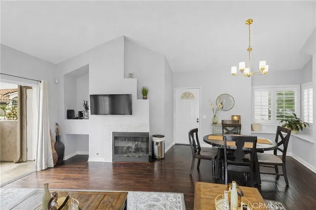 a view of a dining room and livingroom with furniture wooden floor a rug a fireplace and a chandelier