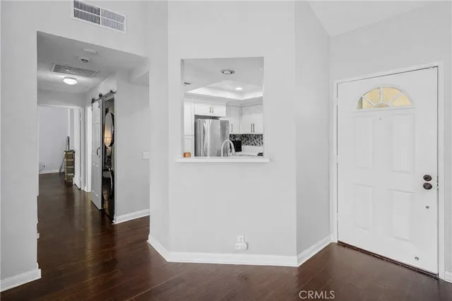 a view of a hallway with wooden floor and a bathroom