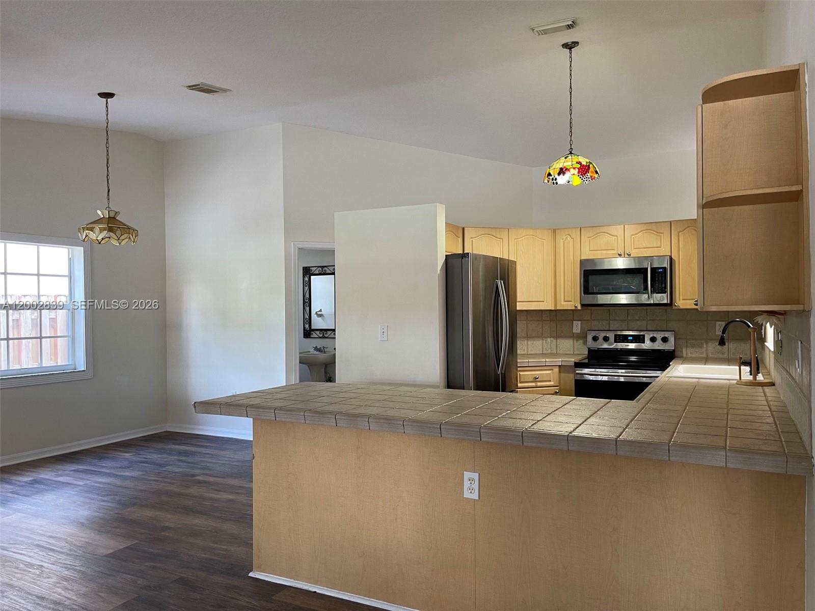 15873 Southwest 43rd Street Miami, FL 33185 - Photo 3 of 23 a kitchen with stainless steel appliances granite countertop a refrigerator a sink a stove and a wooden floors