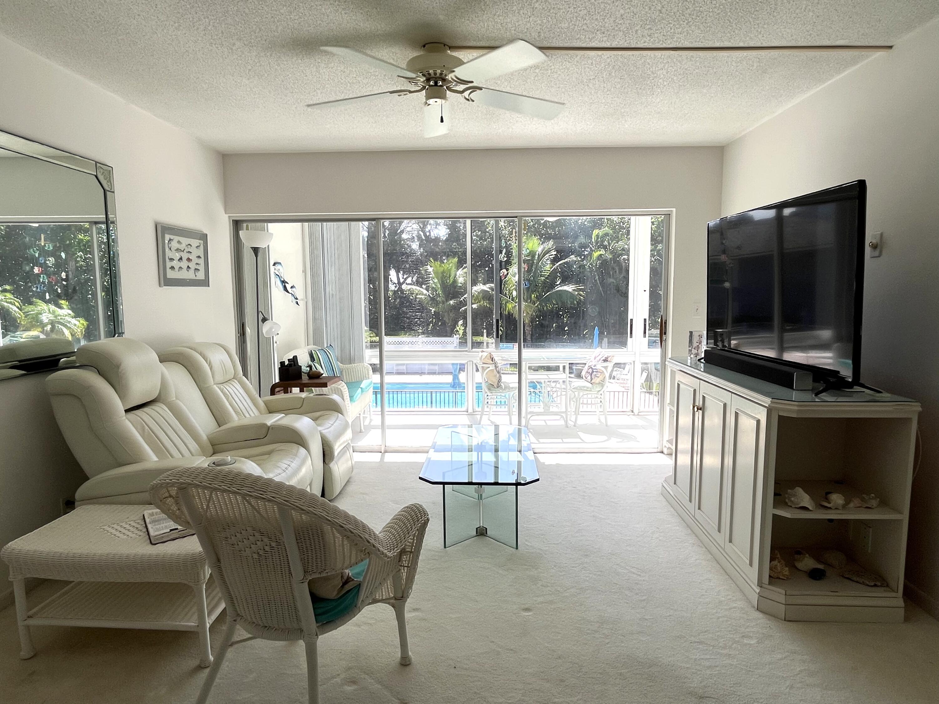 50 Celestial Way, Unit 207 Juno Beach, FL 33408 - Photo 9 of 30 a living room with furniture a flat screen tv and floor to ceiling window