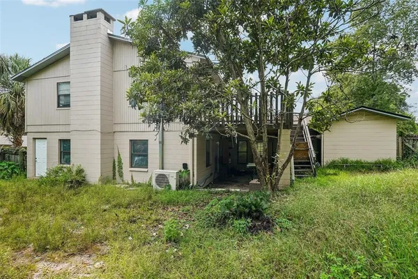 a backyard of a house with plants and large tree