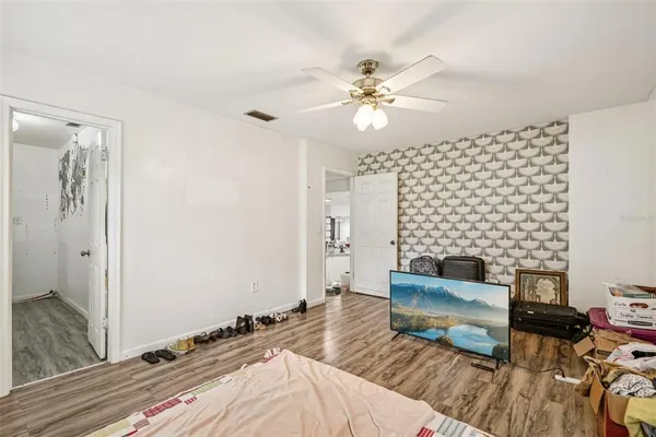 a spacious bedroom with a bed and a chandelier fan