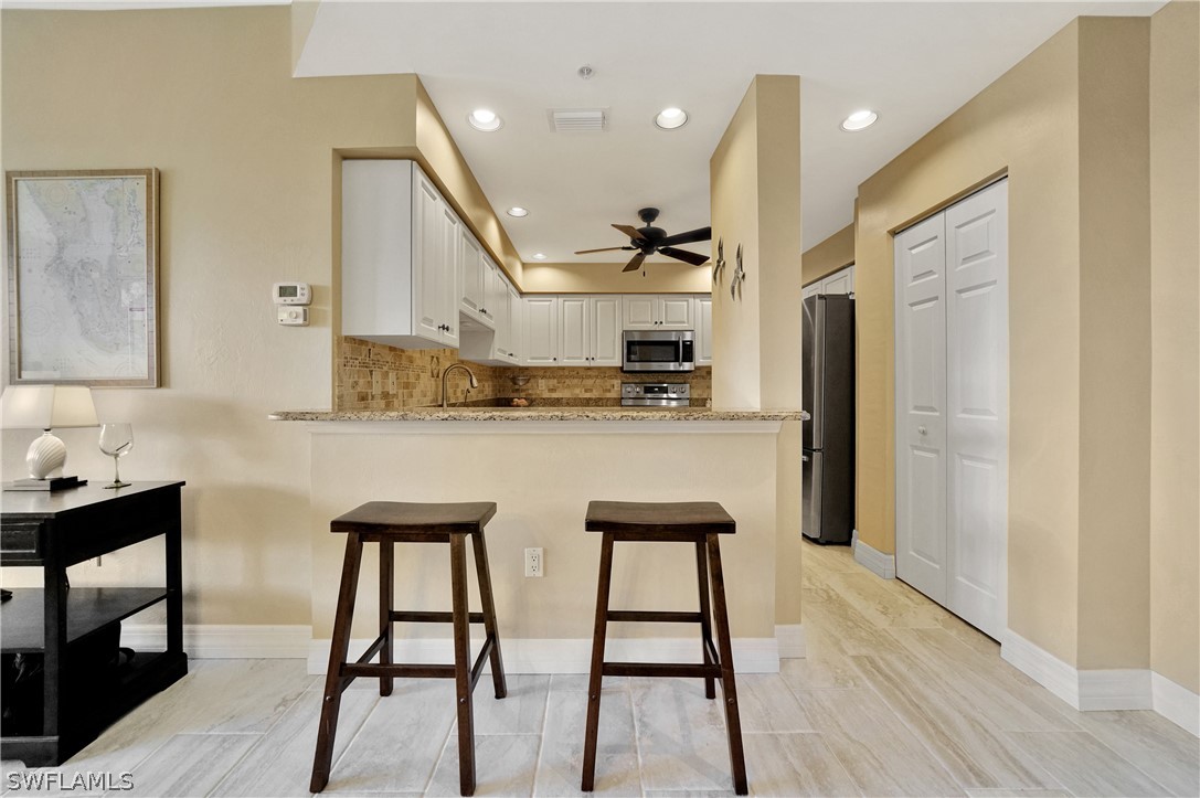 2060 Matecumbe Key Road, Unit 2302 Punta Gorda, FL 33955 - Photo 4 of 30 a kitchen with stainless steel appliances kitchen island granite countertop a table chairs sink and cabinets