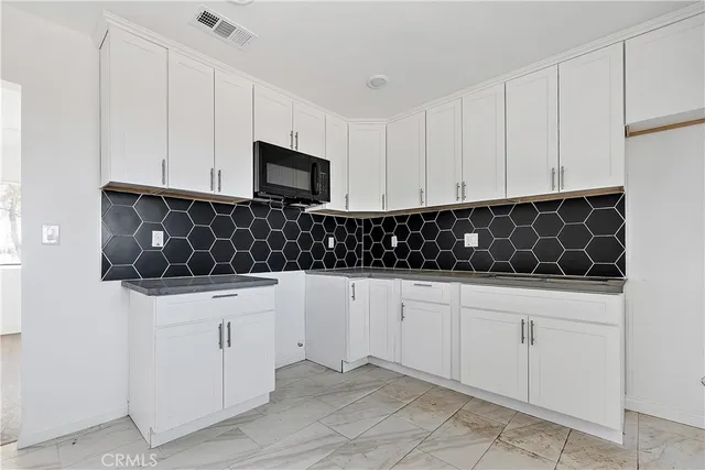 a kitchen with white cabinets and black appliances