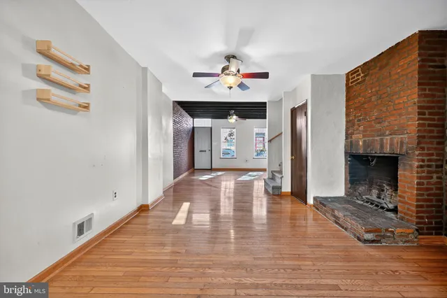 a view of an empty room with wooden floor and a fireplace