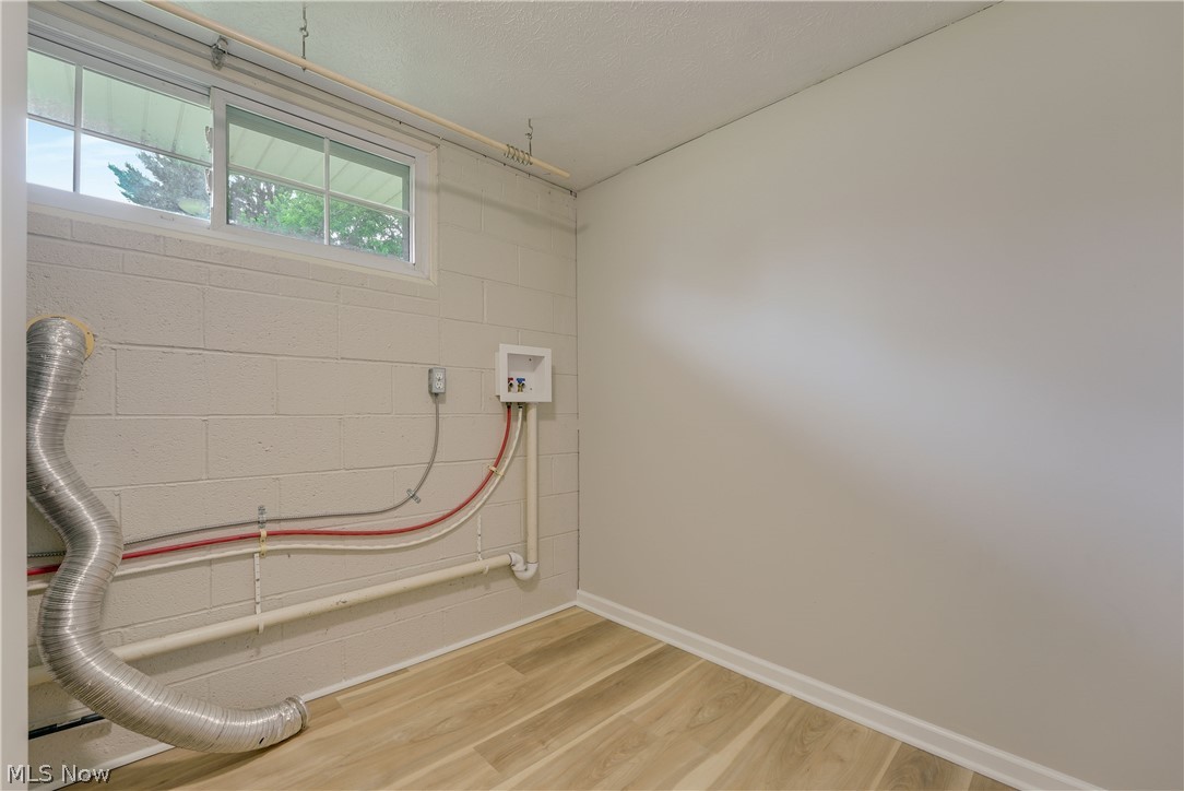 646 Ledge Road Macedonia, OH 44056 - Photo 17 of 28 Utility room featuring wood-finish flooring, white painted block walls, two windows, and exposed plumbing for laundry connections
