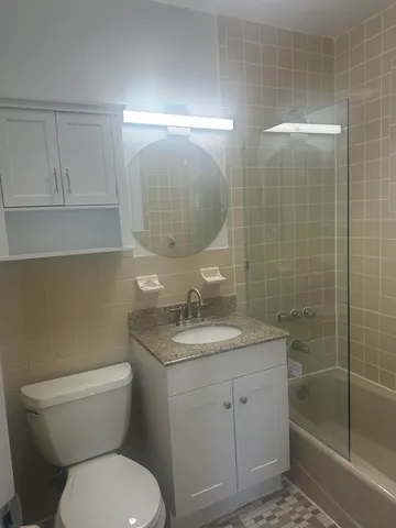 a bathroom with a granite countertop toilet a sink and mirror
