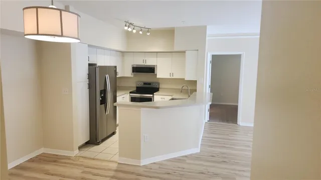 a kitchen view with a refrigerator a stove top oven and cabinets
