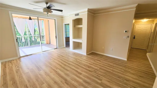 a view of empty room with wooden floor and fan