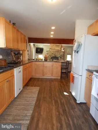 a kitchen with stainless steel appliances granite countertop a refrigerator a sink dishwasher a stove and white countertops with wooden floor