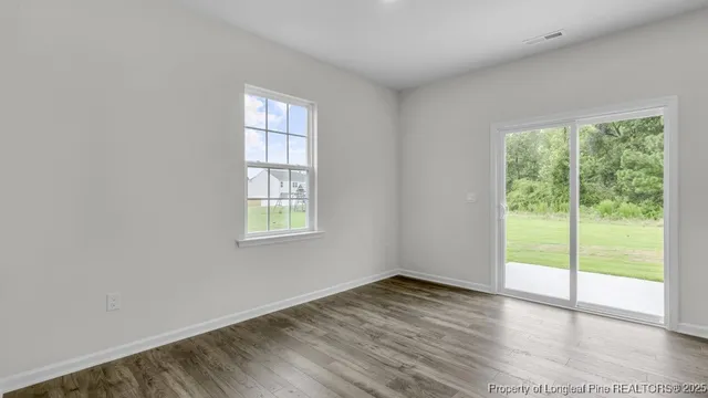 a view of an empty room with wooden floor and windows