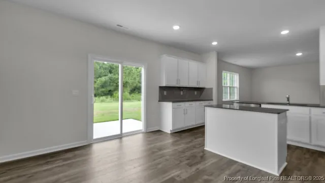 a kitchen with stainless steel appliances a microwave a stove a sink and white cabinets with wooden floor