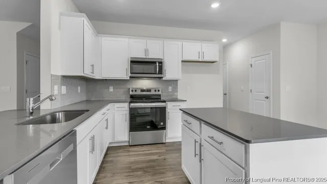 a kitchen with granite countertop a sink and white cabinets