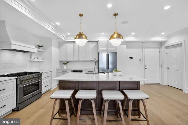 a kitchen with stainless steel appliances a dining table chairs stove and cabinets