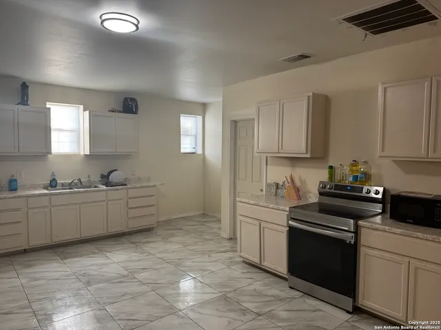 a kitchen with white cabinets and sink