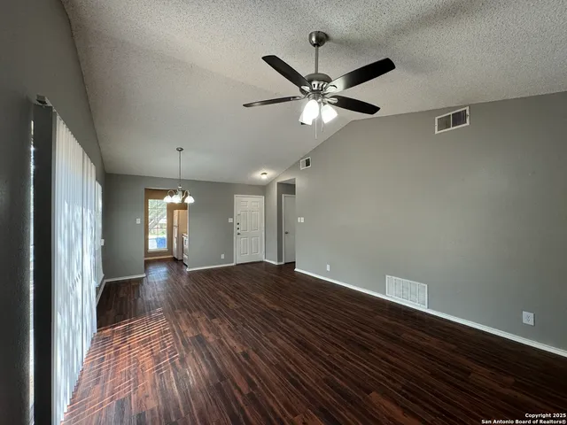 a view of empty room with wooden floor and fan