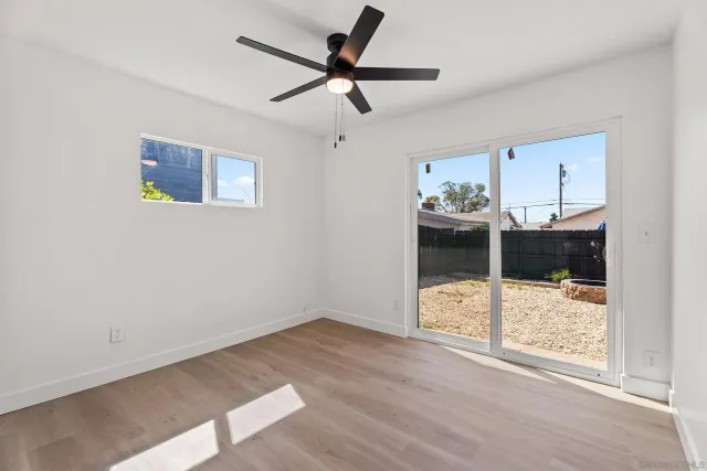 a view of empty room with wooden floor and ceiling fan
