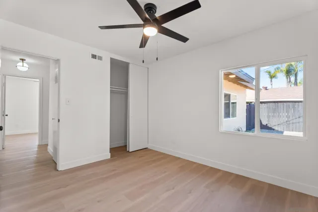 a view of an empty room with a window and wooden floor