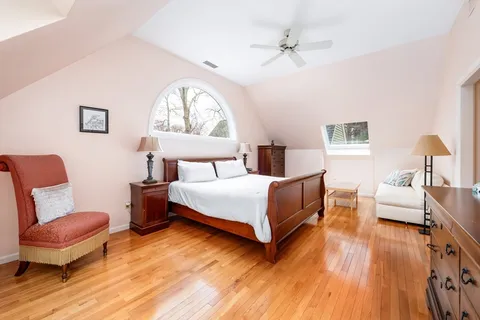 a bedroom with a bed wooden floor and a lamp on dresser with wooden floor