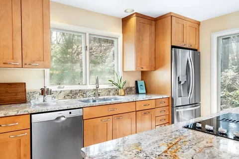 a kitchen with stainless steel appliances granite countertop a refrigerator a sink dishwasher a stove with wooden cabinets and floor