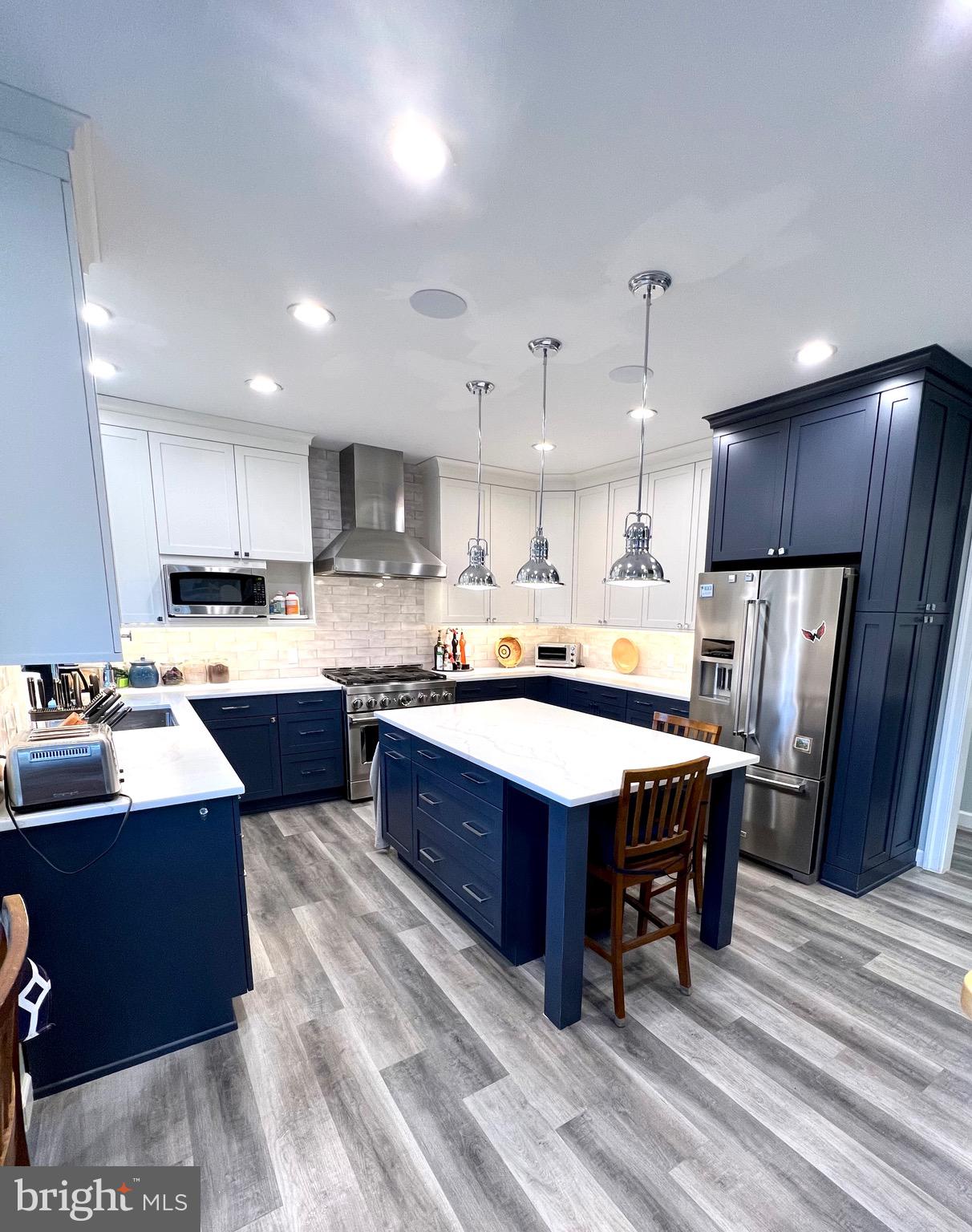 9706 Hidden Valley Road Vienna, VA 22181 - Photo 12 of 43 a kitchen with stainless steel appliances kitchen island granite countertop a table chairs sink refrigerator and microwave