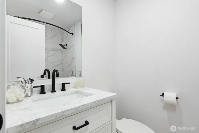 a bathroom with a granite countertop sink mirror vanity and toilet