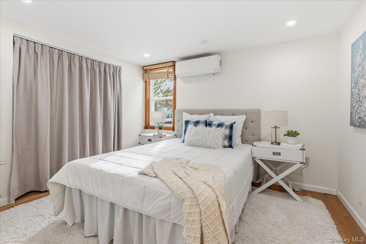 85 Briarcliff Road Westbury, NY 11590 - Photo 12 of 31 Bedroom with wood finished floors, an AC wall unit, and recessed lighting