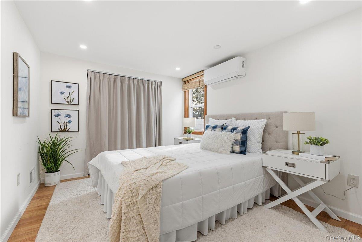 85 Briarcliff Road Westbury, NY 11590 - Photo 13 of 31 Bedroom featuring a wall unit AC, light wood-style flooring, and recessed lighting