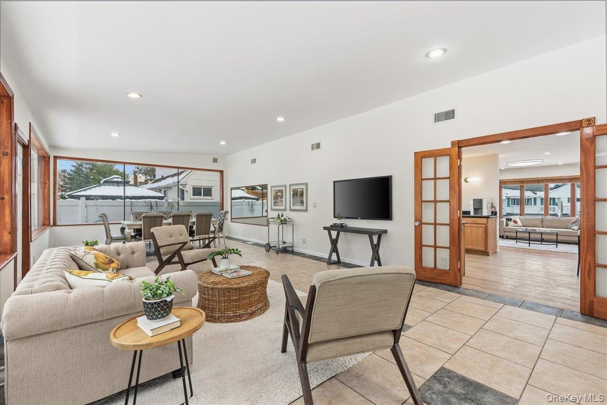 85 Briarcliff Road Westbury, NY 11590 - Photo 15 of 31 Living room with light tile patterned floors, recessed lighting, french doors, and a sunroom