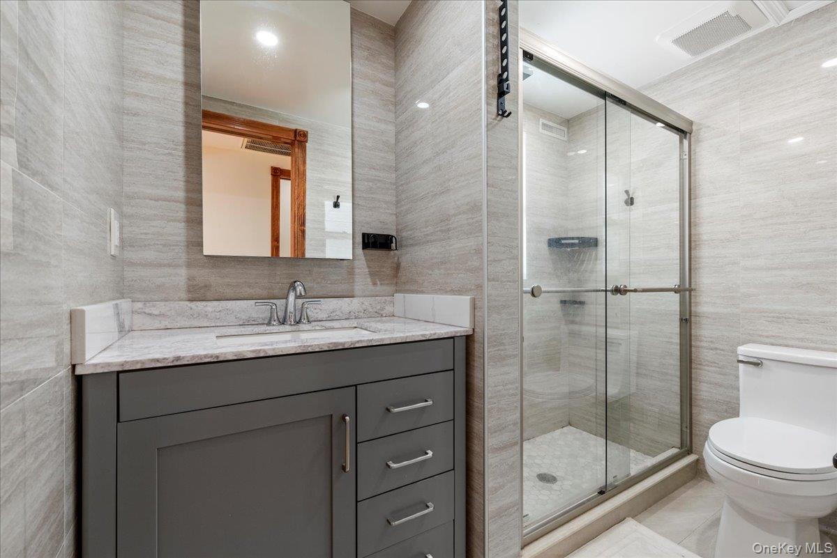 85 Briarcliff Road Westbury, NY 11590 - Photo 22 of 31 Full bathroom with vanity, tile walls, and a shower stall
