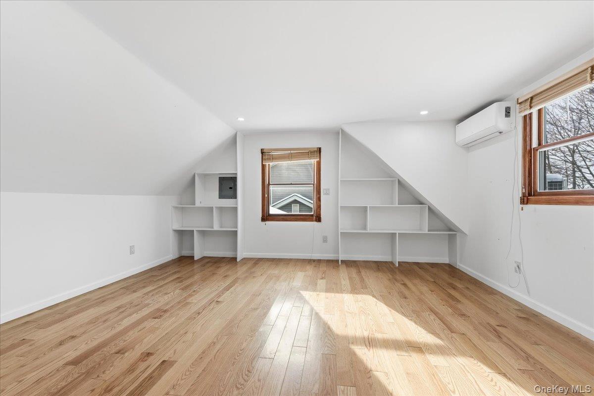 85 Briarcliff Road Westbury, NY 11590 - Photo 23 of 31 Additional living space featuring light wood-type flooring, a wall mounted air conditioner, built in shelves, and vaulted ceiling