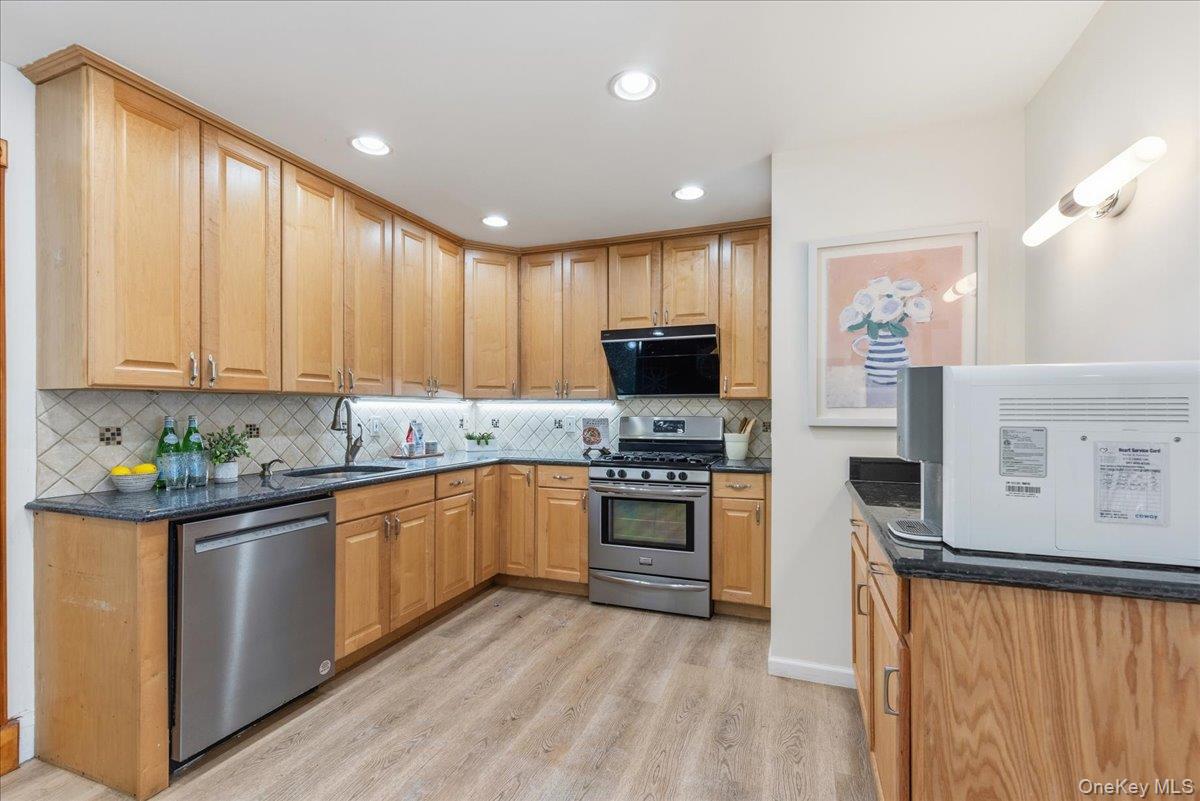 85 Briarcliff Road Westbury, NY 11590 - Photo 7 of 31 Kitchen featuring appliances with stainless steel finishes, dark stone counters, light wood-type flooring, recessed lighting, and tasteful backsplash