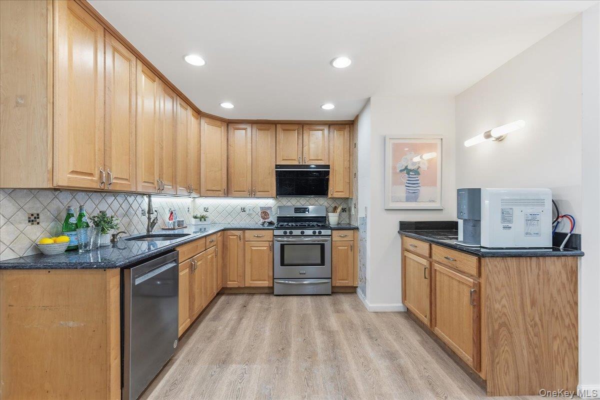 85 Briarcliff Road Westbury, NY 11590 - Photo 8 of 31 Kitchen with dark stone countertops, appliances with stainless steel finishes, light wood finished floors, recessed lighting, and decorative backsplash