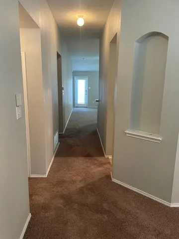a view of a hallway with wooden floor and a bathroom