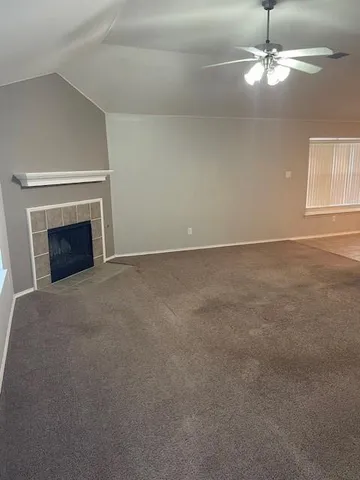 an empty room with chandelier fan and fireplace