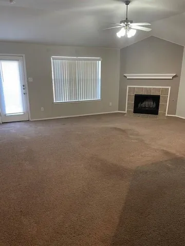 an empty room with chandelier fan and windows