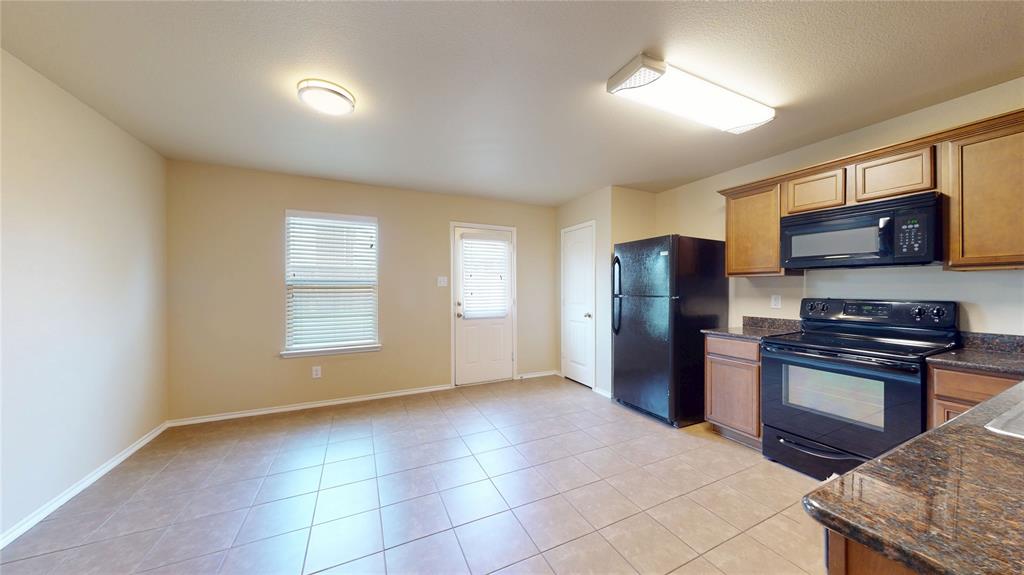 471 Harding Lane Lavon, TX 75166 - Photo 6 of 19 Kitchen featuring black appliances, dark stone countertops, light tile patterned floors, and wood finish cabinetry