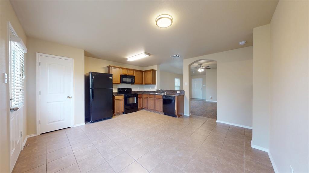 471 Harding Lane Lavon, TX 75166 - Photo 8 of 19 Kitchen with black appliances, dark countertops, a ceiling fan, wood finish cabinets, and light tile patterned floors