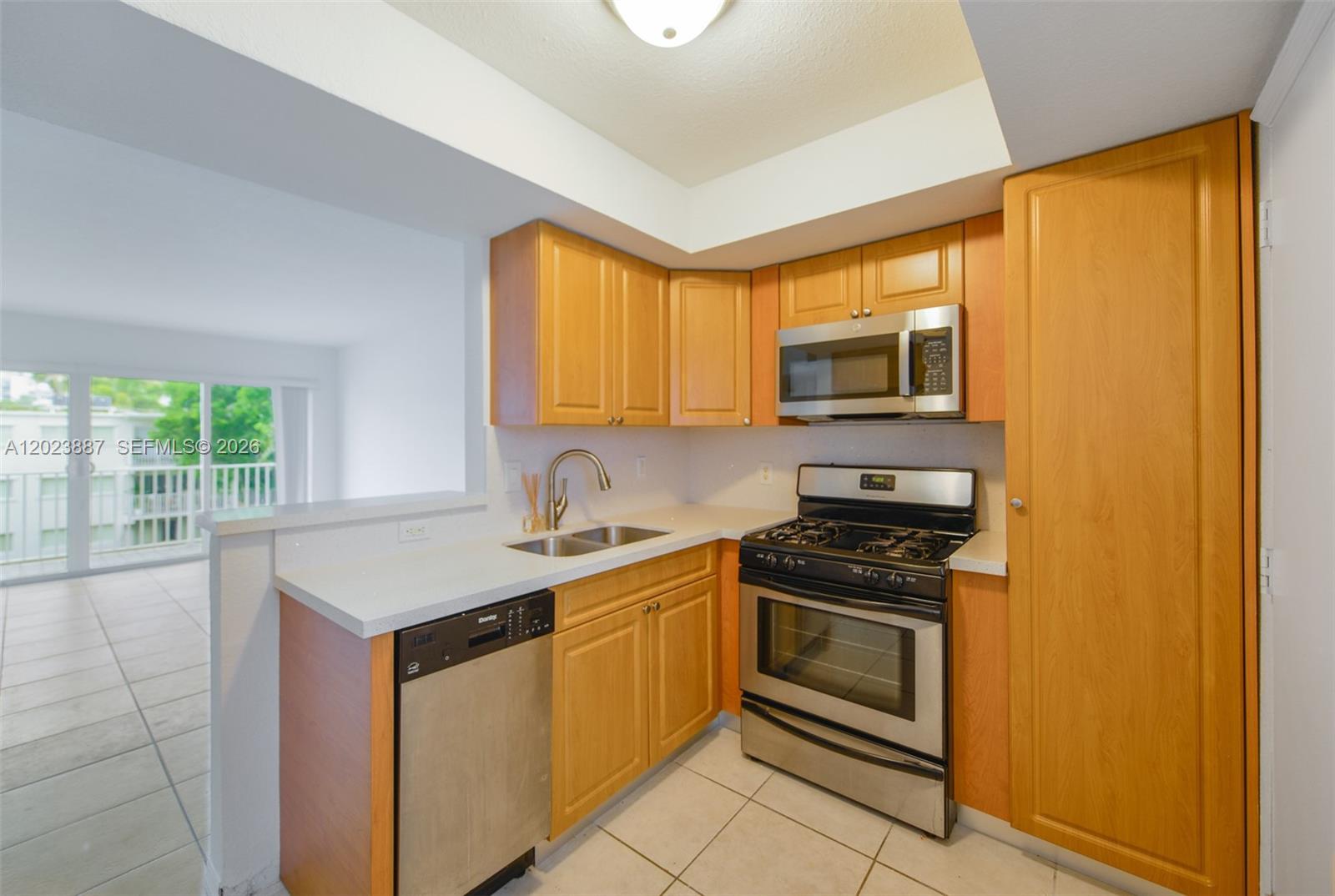 7737 Southwest 88th Street, Unit C312 Miami, FL 33156 - Photo 8 of 32 a kitchen with stainless steel appliances granite countertop a stove a sink and a microwave