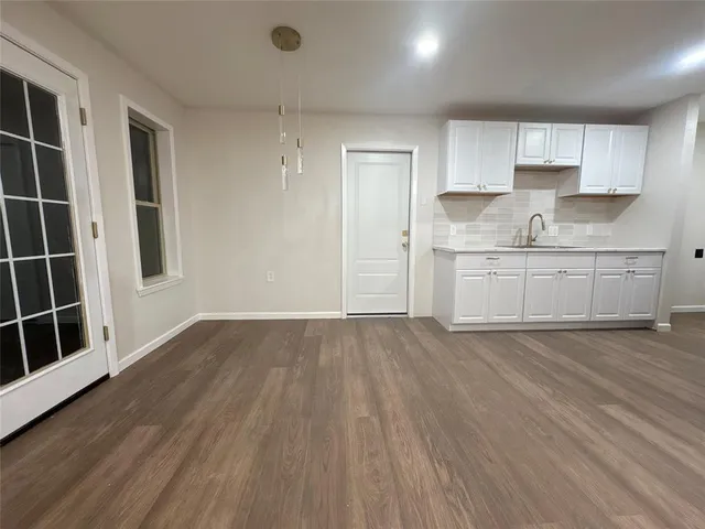 a kitchen with granite countertop white cabinets and wooden floor