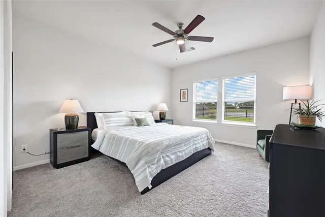 a spacious bedroom with a bed a chandelier and a large window