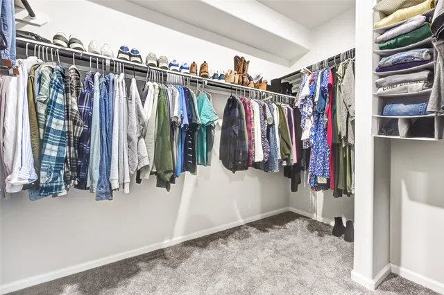 a view of walk in closet with clothes and shoes