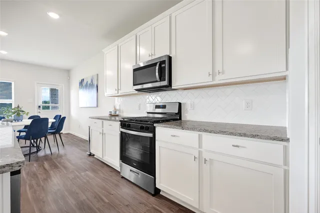 a kitchen with granite countertop white cabinets and stainless steel appliances