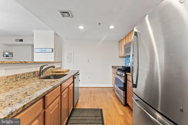 a kitchen with granite countertop stainless steel appliances a sink stove top oven and refrigerator